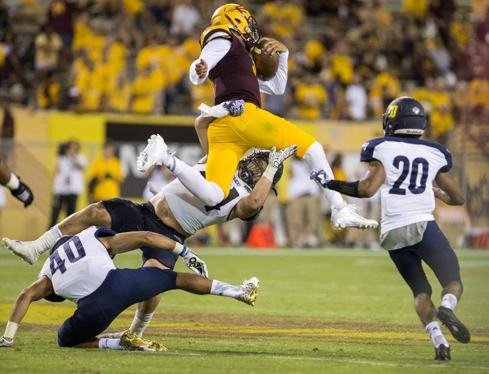 ASU redshirt sophomore quarterback Manny Wilkins (5) hops over defenders during a game against Northern Arizona University in Tempe, Arizona, on Sept. 3, 2016. The Sun Devils won the matchup, 44-13.
