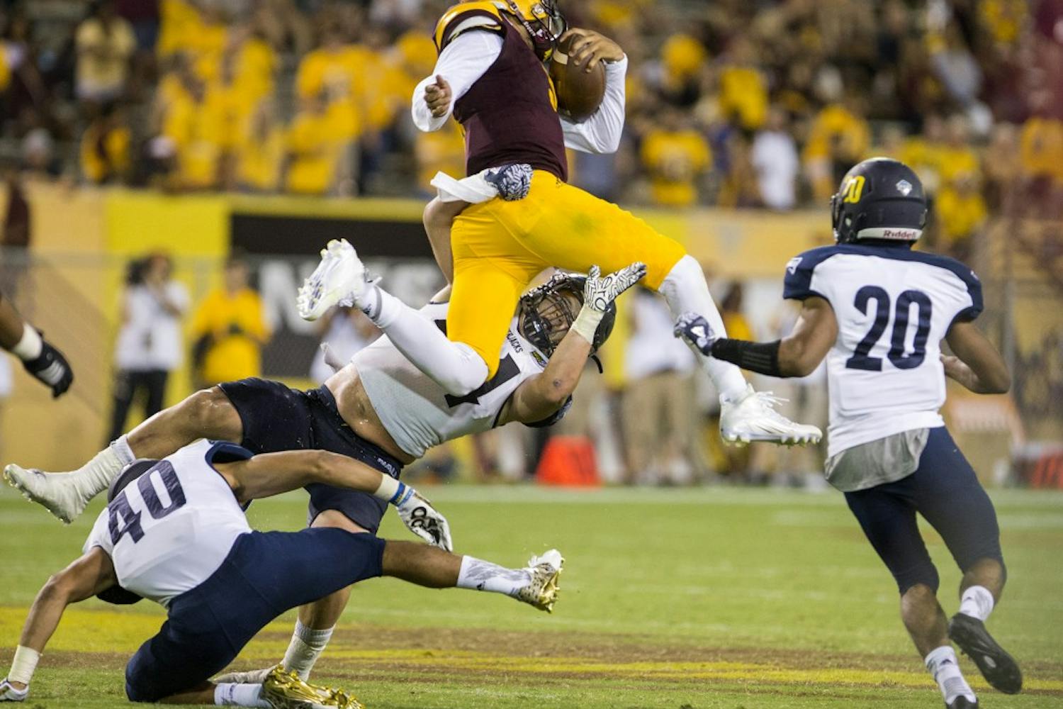 ASU redshirt sophomore quarterback Manny Wilkins (5) hops over defenders during a game against Northern Arizona University in Tempe, Arizona, on Sept. 3, 2016. The Sun Devils won the matchup, 44-13.