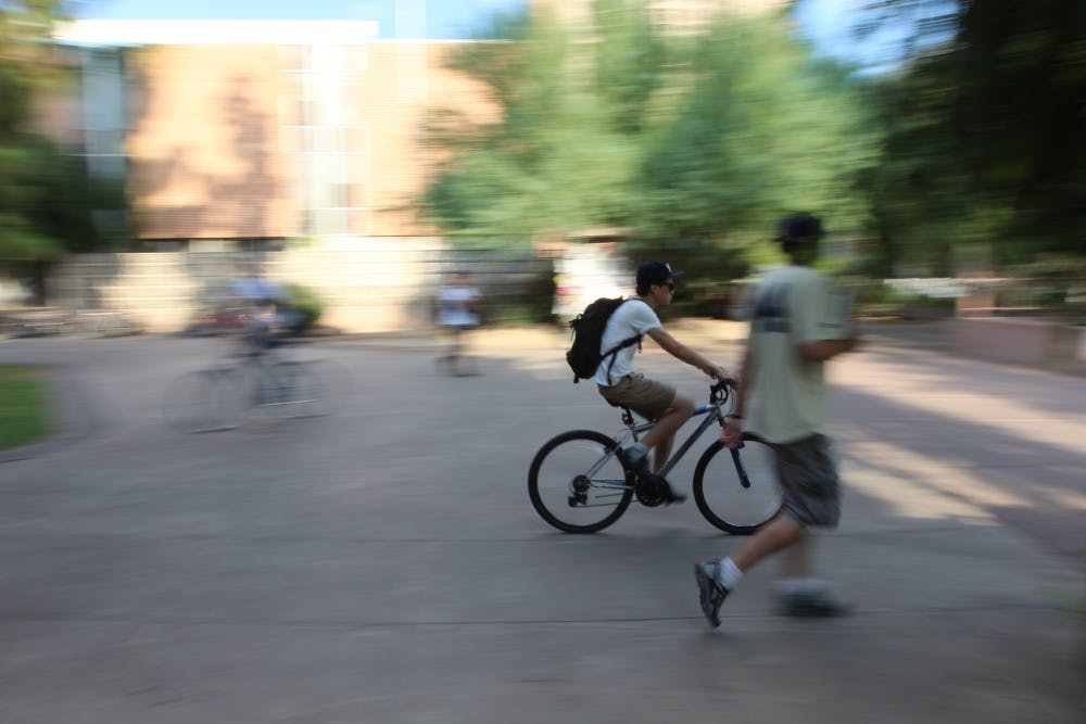 An ASU student narrowly rides by a pedestrian on the Tempe campus. Tempe police officers were out this week passing around warnings and giving out advice on how to ride safely around ASU and on the streets in Tempe. (Photo by Dominic Valente)