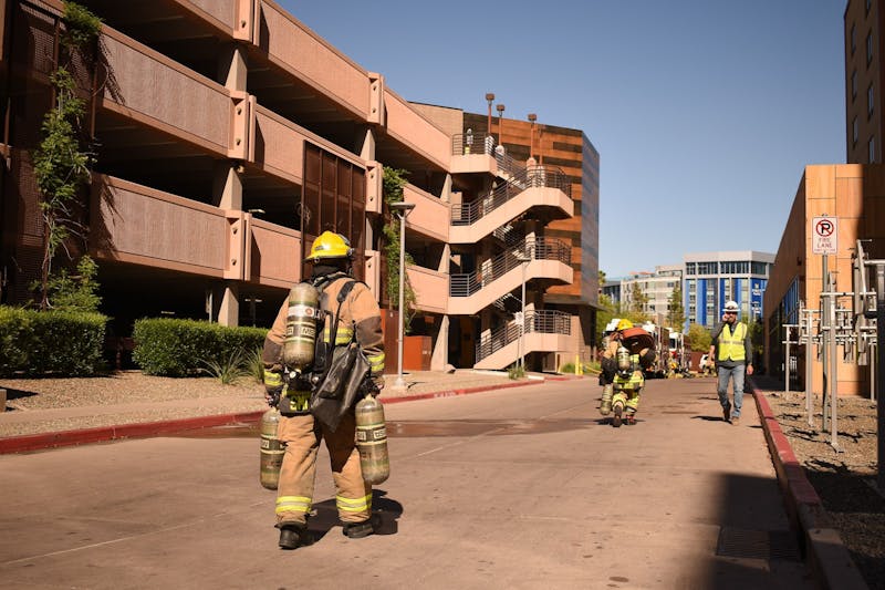 A firefighter walks between a parking garage and Tooker House in Tempe on April 19, 2024.