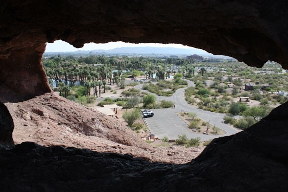 RED-ROCK VIEW: South Mountain and Southern Phoenix are framed within the tafoni (hole) in the rocks in Papago Peak. (Photo by Kyle Thompson)