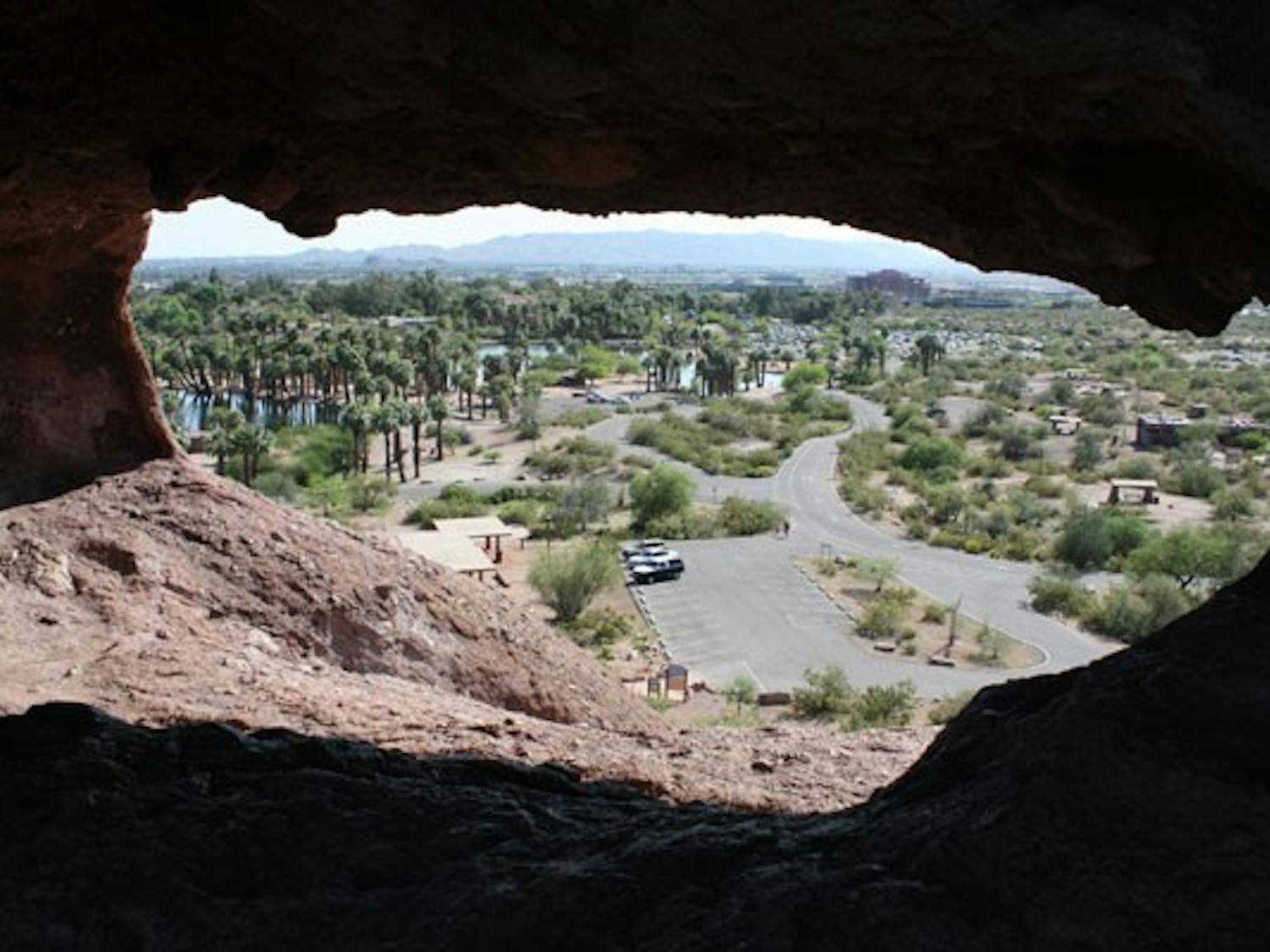 RED-ROCK VIEW: South Mountain and Southern Phoenix are framed within the tafoni (hole) in the rocks in Papago Peak. (Photo by Kyle Thompson)