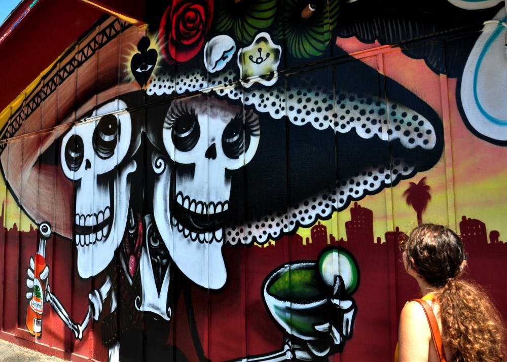 Fibers art student Gabrielle Llovet views Cota’s mural on Tacos de Juarez. Photo by Trent Bowen