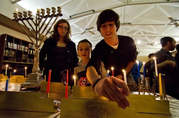 FESTIVAL OF LIGHTS: Jake Stein and Diana Lustig, both freshmen at the Cronkite School of Journalism, light candles in celebration of the first night of Hanukkah at the ASU Chabad House. (Photo by Aaron Lavinsky)