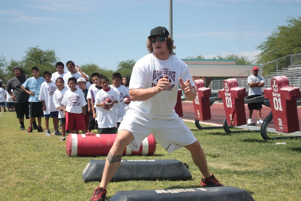 Junior offensive lineman Dan Knapp demonstrates proper blocking technique to campers at San Carlos High School. (Photo by Nick Kosmider)
