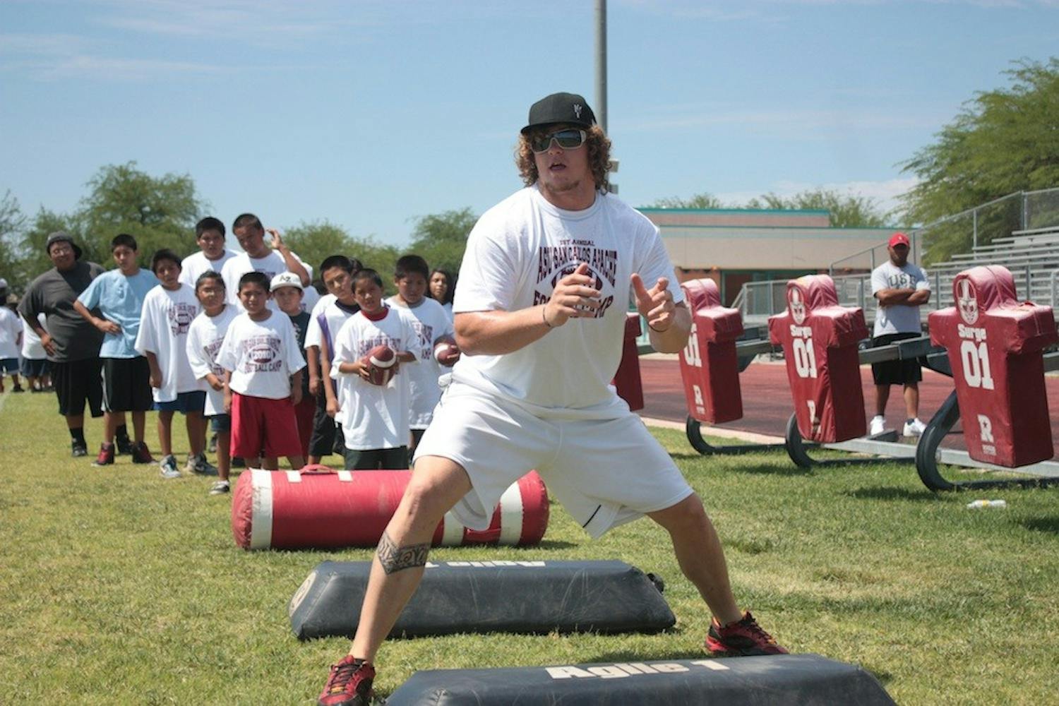 Junior offensive lineman Dan Knapp demonstrates proper blocking technique to campers at San Carlos High School. (Photo by Nick Kosmider)