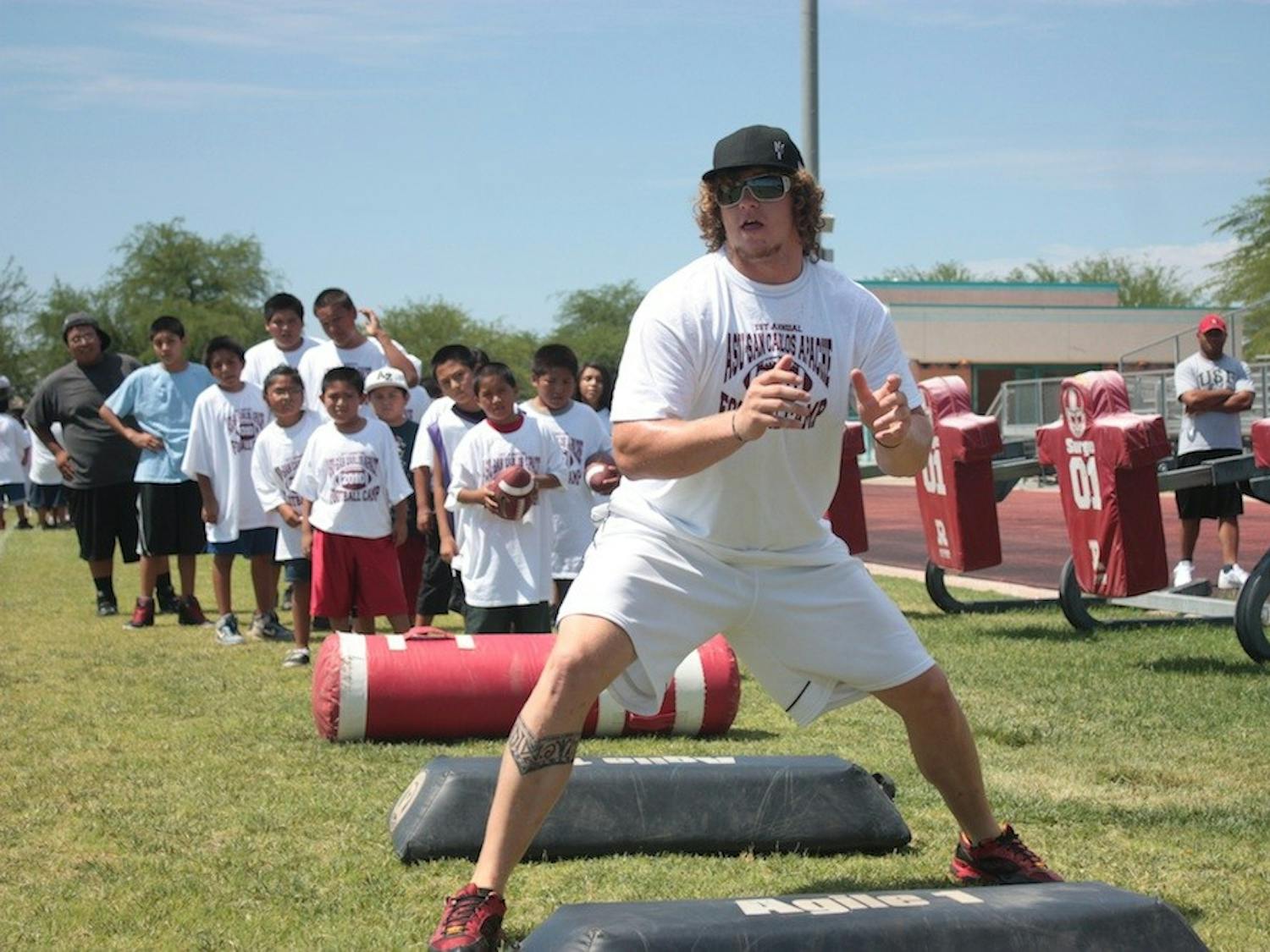 Junior offensive lineman Dan Knapp demonstrates proper blocking technique to campers at San Carlos High School. (Photo by Nick Kosmider)