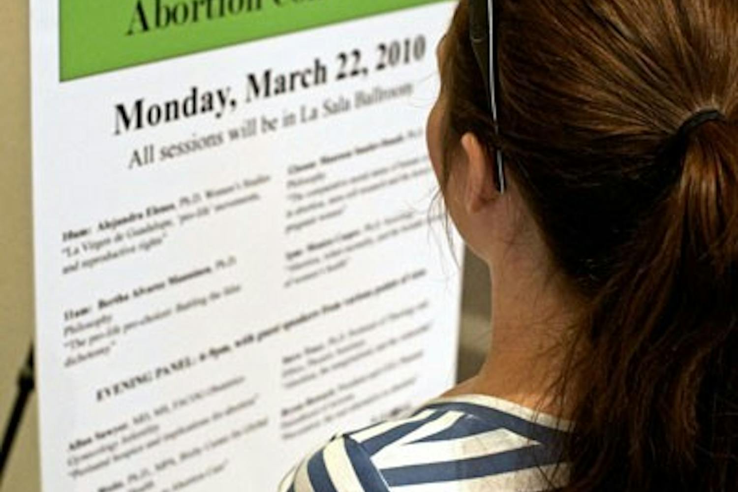THE HOT TOPIC: A student on the West campus previews the day's schedule for the daylong abortion-themed conference. "Seeking Coverage in the Abortion Controversy" features various ASU professors who speak on topics ranging from stem cell research to infant mortality. (Photo by Michael Arellano)