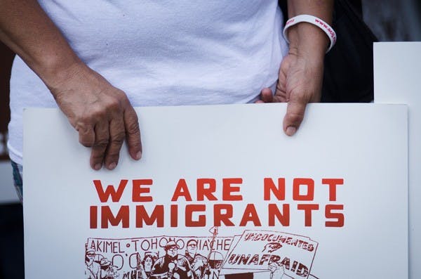 A protester holds an anti SB 1070 sign during a protest Sept. 19 outside of the Immigration and Customs Enforcement field office in downtown Phoenix. (Photo by Aaron Lavinsky)