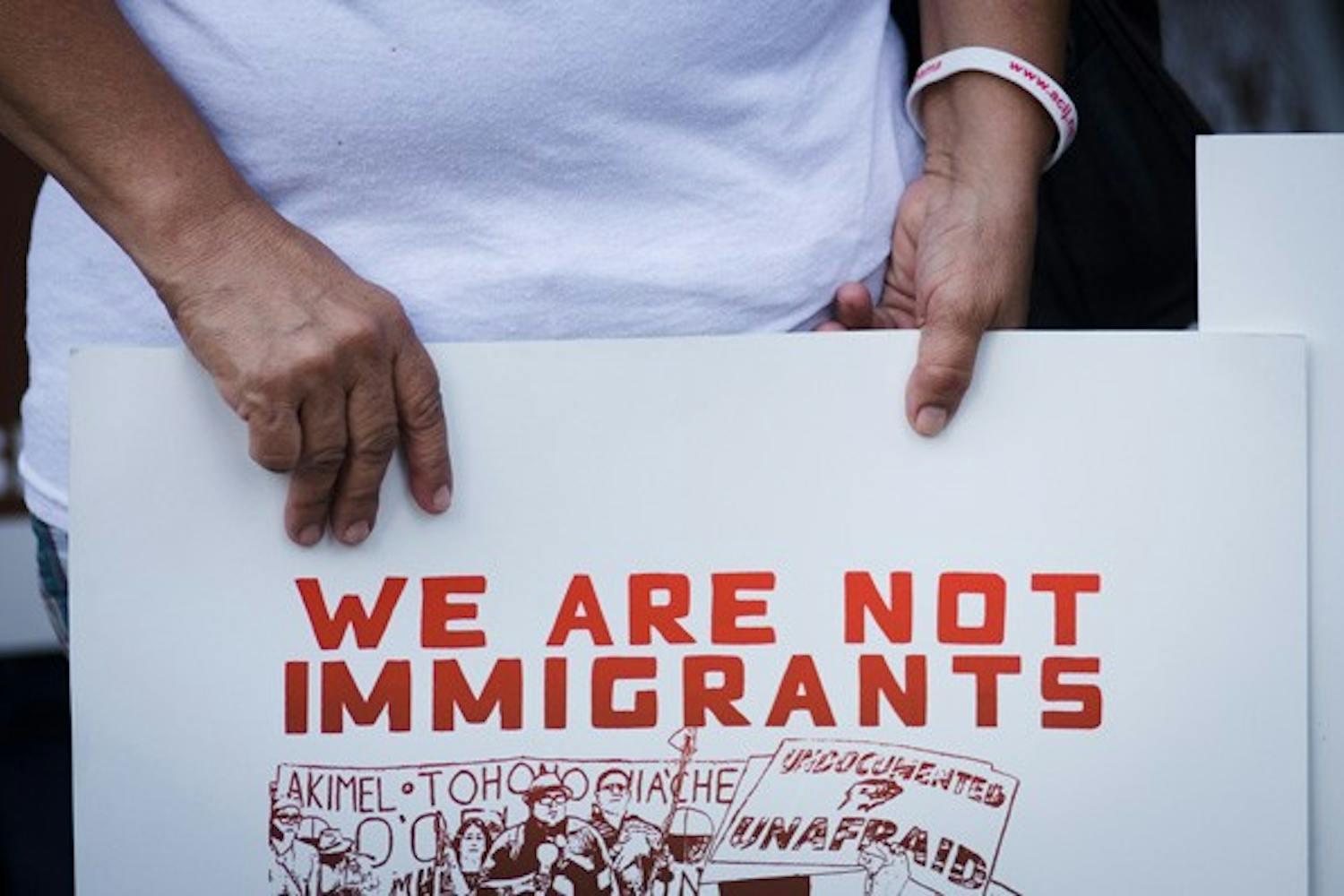 A protester holds an anti SB 1070 sign during a protest Sept. 19 outside of the Immigration and Customs Enforcement field office in downtown Phoenix. (Photo by Aaron Lavinsky)