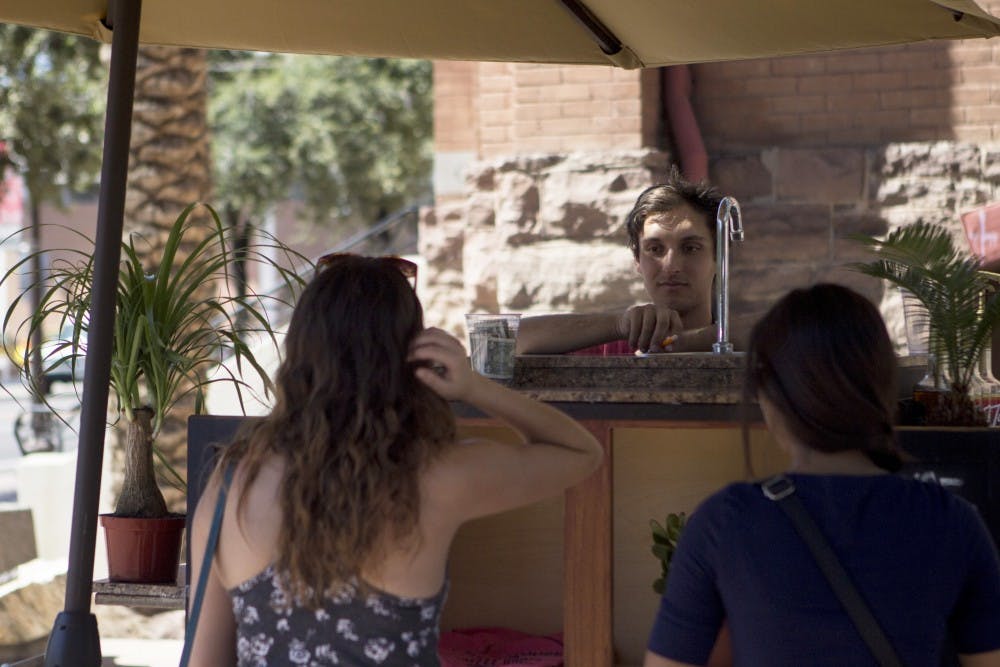Economics junior Nick Dipastena serves customers for the Blue House coffee cart in Tempe. Dipastena said that the Blue House coffee team will soon have a trailer for their cart, and will have more mobility on campus in the near future. (Photo by Dominic Valente)