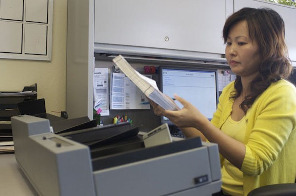 SCANTRON READERS: ASU employee Amy Li p[laces the scantrons in the grading machine. Li is one of the two Scantron-processing employees at ASU and together, they process hundreds of thousands of scantrons a year. (Photo by Scott Stuk)