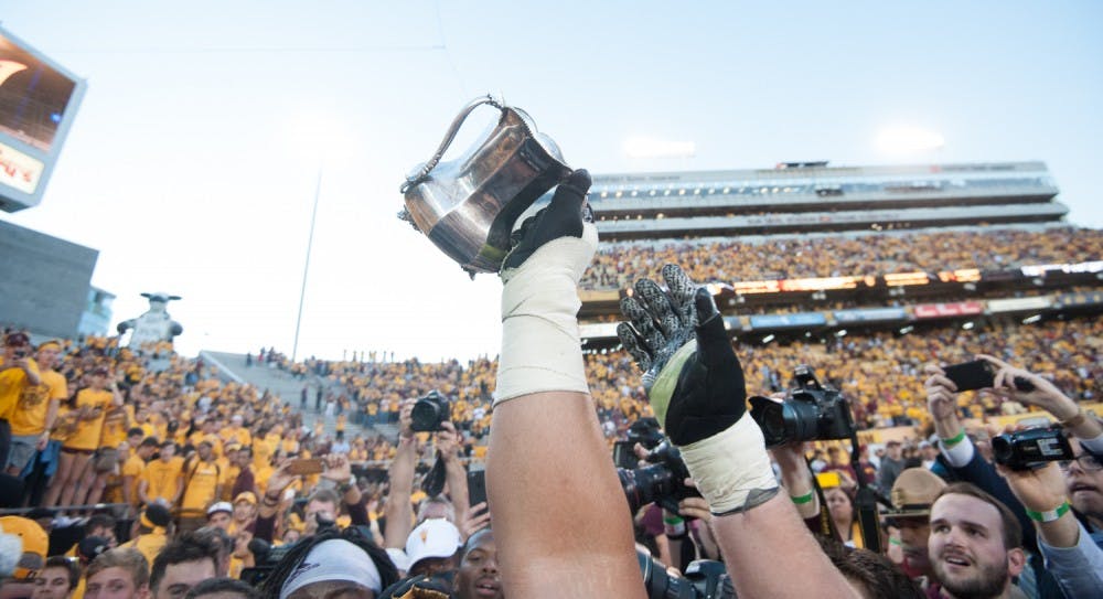 ASU football players lift the Territorial Cup in celebration after defeating UA on Saturday, Nov. 21, 2015, at Sun Devil Stadium in Tempe.