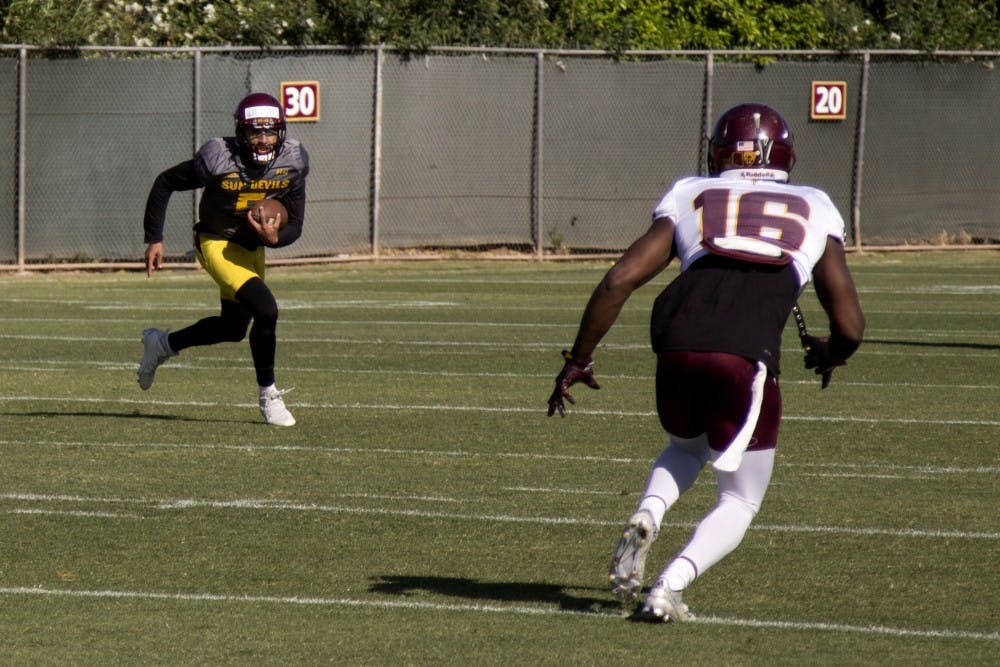 Redshirt sophomore quarterback Manny Wilkins (5) scrambles as De'Chavon 'Gump' Hayes runs toward him during a scrimmage on Friday, March 25, 2016.
