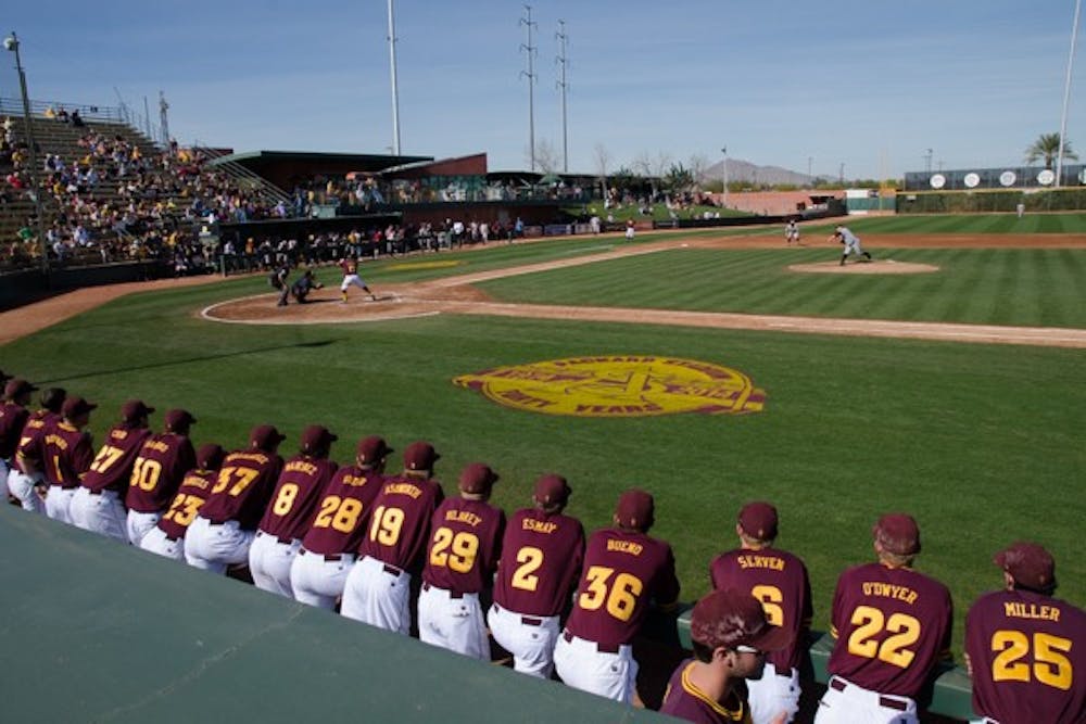 Current Sun Devil baseball players watch from the dugout as former Sun Devil baseball players compete against them during the 2014 Alumni Game. The current team beat the alumni 11-5 at the final installment of the game at Packard Stadium on Feb. 11.