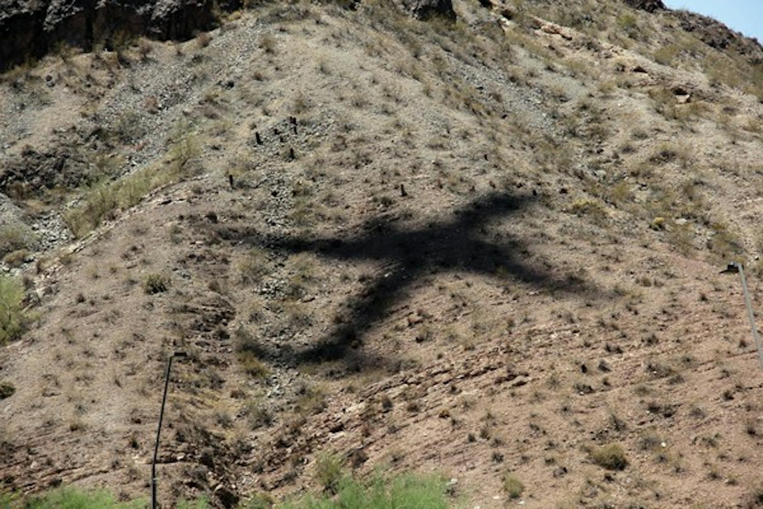 As a commerical airliner heads in to land at Phoenix Skyharbor International Airport Sunday morning, it casts a large shadow on Tempe's Hayden Butte, locally known as A-Mountain. (Photo by Shawn Raymundo)