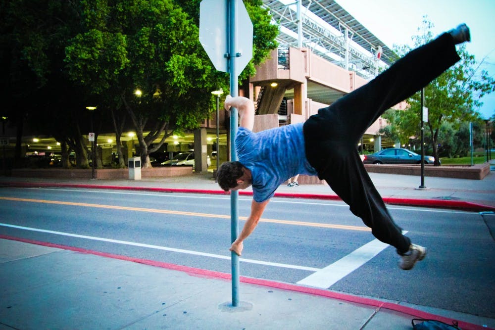 Showing his strength and balance, Caban lifts himself off the ground and twirls around a stop sign.
Photo by Cristina Melian