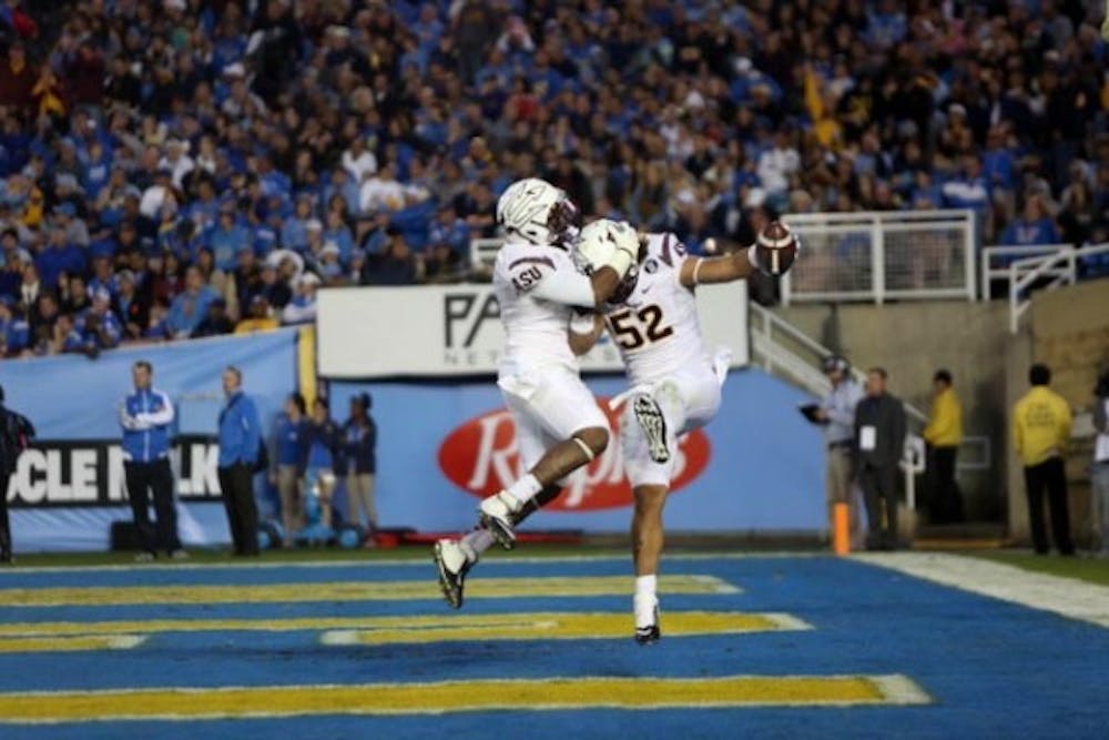 Redshirt junior defensive end Carl Bradford celebrates his touchdown with senior linebacker Chris Young. ASU defeated the Bruins 38-33 and clinched a spot in the Pac-12 championship. (Photo by Dominic Valente.)