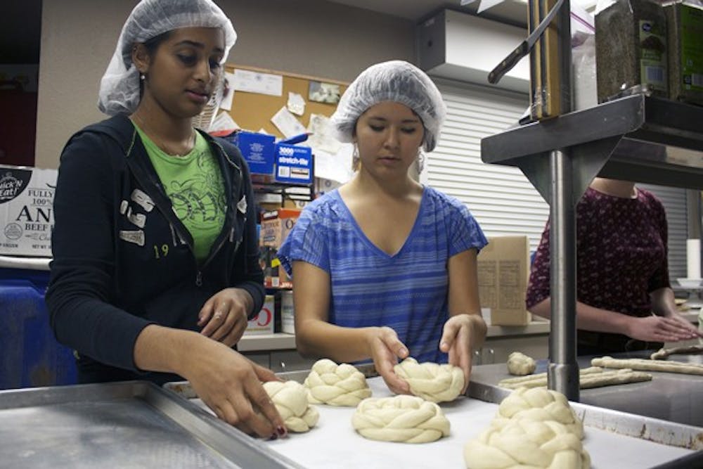 Health science freshman Sonia Kunthara and biomedical engineering freshman Allaina Honda lay the challah dough on the tray before putting it through the oven to sell for $4 a loaf at the ASU farmer's market Tuesday on the Tempe campus. All proceeds went to United Foods and the American Jewish World Service efforts in Sudan and Darfur. (Photo by Shawn Raymundo)