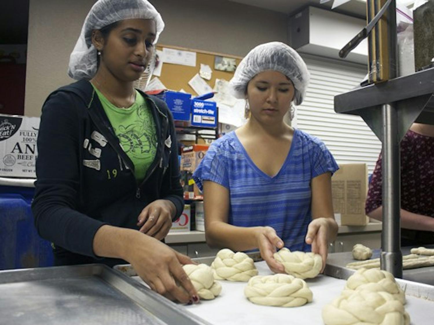 Health science freshman Sonia Kunthara and biomedical engineering freshman Allaina Honda lay the challah dough on the tray before putting it through the oven to sell for $4 a loaf at the ASU farmer's market Tuesday on the Tempe campus. All proceeds went to United Foods and the American Jewish World Service efforts in Sudan and Darfur. (Photo by Shawn Raymundo)