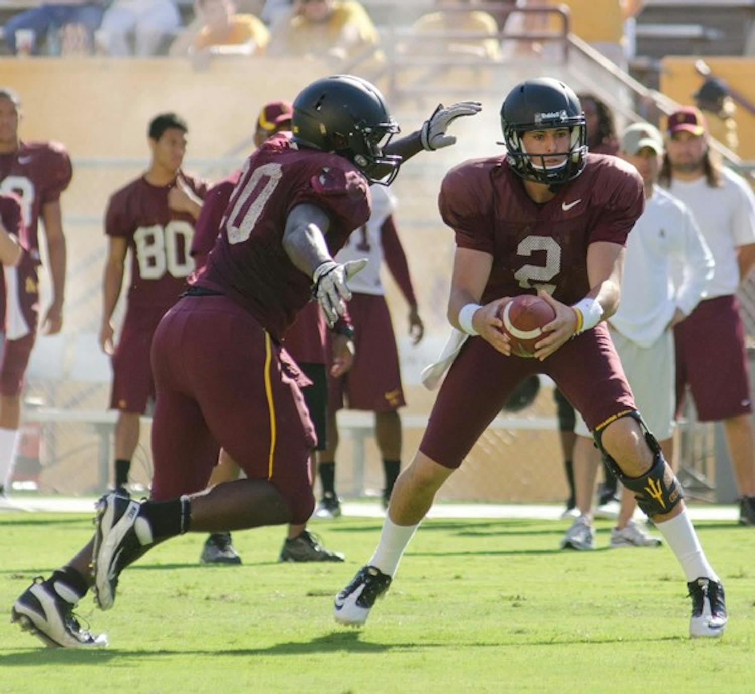 POSITION BATTLE: Freshman backup quarterback Mike Bercovici hands off the ball to redshirt freshman running back Marcus Washington during Saturday’s scrimmage. Head coach Dennis Erickson has yet to decide whether Bercovici or redshirt freshman Taylor Kelly will be the no. 2 quarterback. (Photo by Aaron Lavinsky)