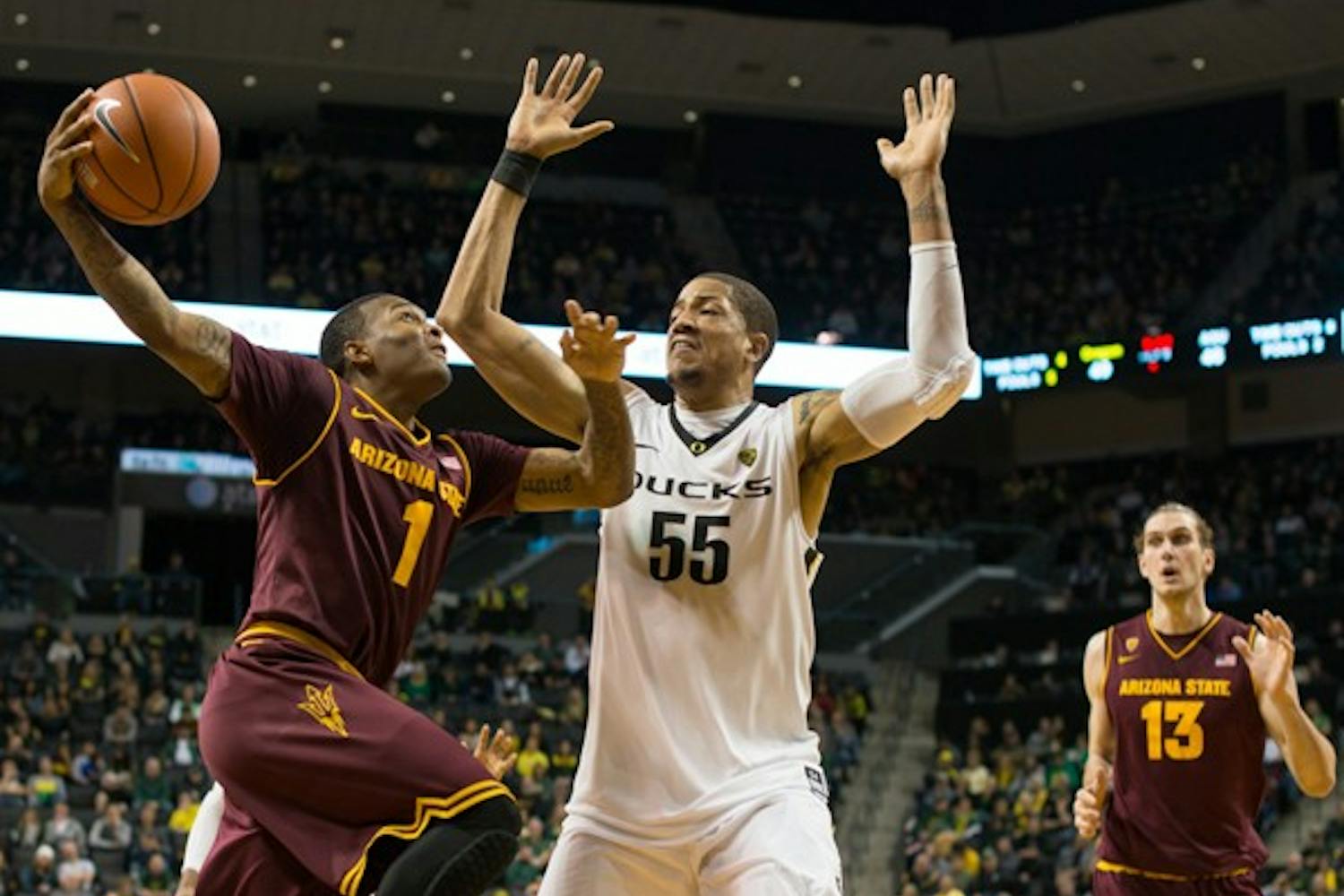 Freshman guard Jahii Carson drives to the basket under heavy pressure from Oregon center Tony Woods. The Oregon Ducks defeated the ASU Sun Devils 68-65 at Matt Knight Arena on January 13th, 2013. (Courtesy of Michael Arellano)