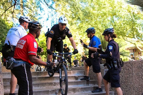 An officer practices riding down stairs as spotters watch.  Learning to ride safety over many types of terrain is a valuable part of the International Police Mountain Bike Association course curriculum.