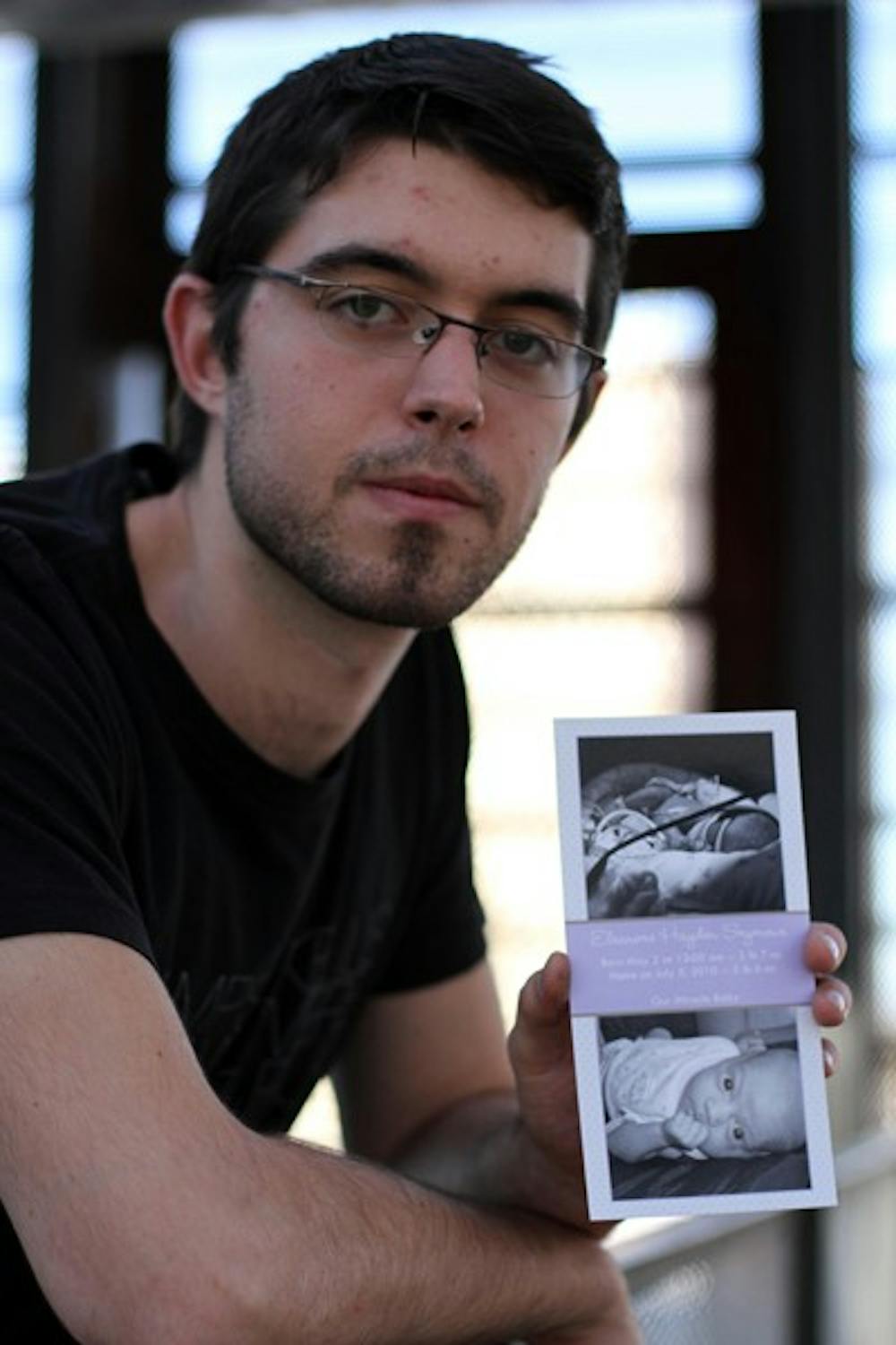 IN REMEMBRANCE: Mechanical engineering senior Peter Seymour holds the birth announcement of his daughter Eleanore, who passed away in August 2010 from Sudden Infant Death Syndrome.  Seymour is creating a device that monitors vital signs and can be accessed from a smartphone application. (Photo by Lisa Bartoli)