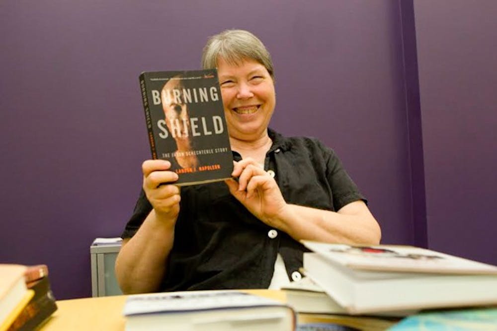 ASU Book Group member Laura Hogue holds up next month's book reading called "Burning Shield" on Sept. 2.