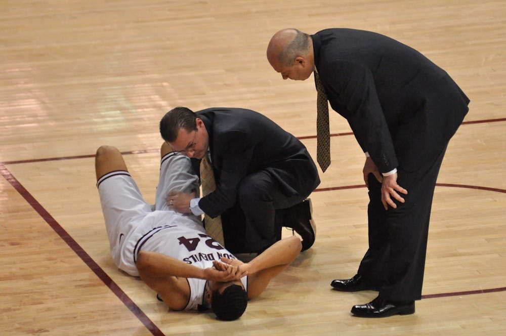 Trent Lockett's ankle is examined on the court by a trainer and coach Herb Sendek after he injured it with 10 minutes remaining in the game. Sendek told reporters during the postgame press conference that Lockett's x-ray results came back negative and that Lockett had badly sprained his ankle.  (Photo by Aaron Lavinsky)