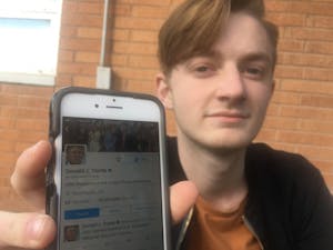 Cooper Newnam, a freshman industrial design student, holds up his iPhone featuring the Twitter account of President Trump 