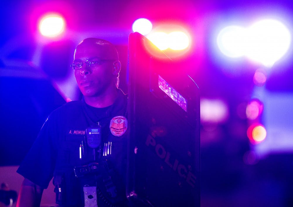 An ASU police officer carries a blast shield back to his car during a police incident near Apache Boulevard in Tempe in the early hours of Saturday, March 18, 2017.