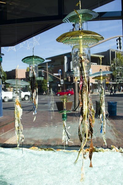Art sculptures made of recycled materials, including USB cords, wires, glass, and yarn, are on display in the windows of the US Post Office on Mill Avenue as part of Tempe Green Revolution. (Photo by Ana Ramirez)