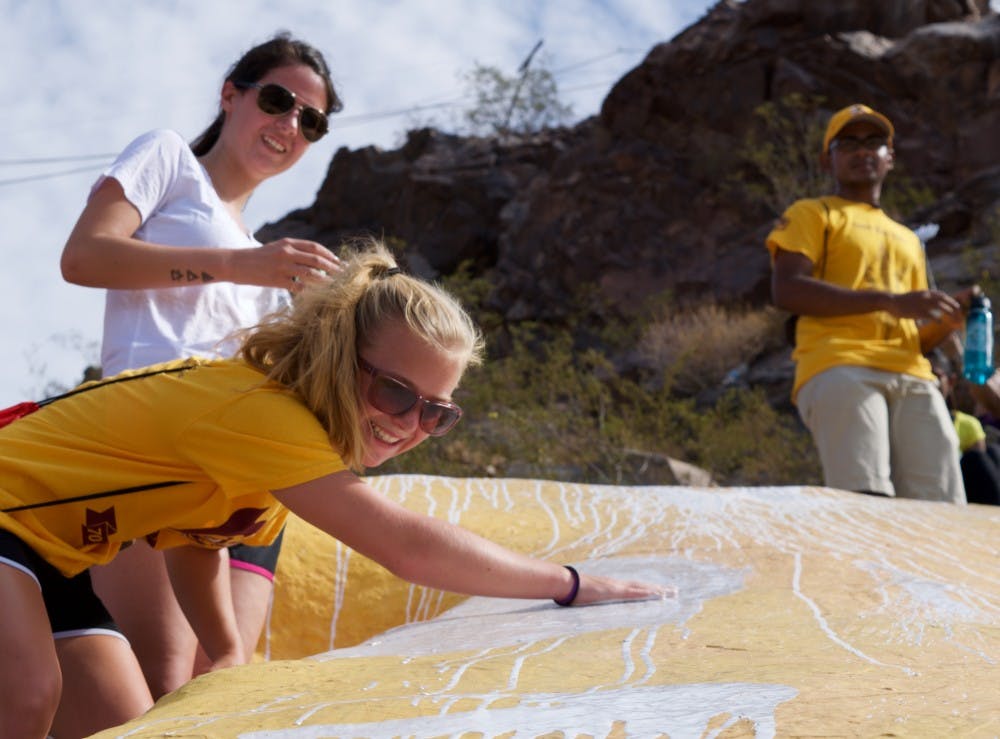 Freshman speech and hearing science major Amanda Mael and freshman art and education major Liz Wagstaff add their cups of paint to the A on Hayden Butte, also known as A Mountain, in Tempe, Arizona, on Aug. 20, 2016. Hundreds of students hike the mountain every fall to add a fresh coat of white paint to the A that sits on the hillside. 
