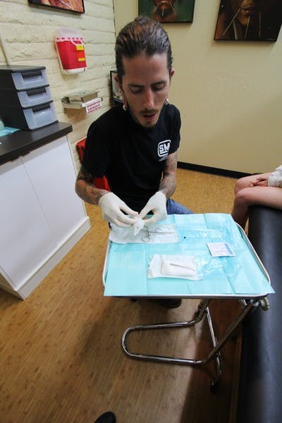Kevin Jump gets ready to give a piercing, a routine part of his job the he's been doing for 17 years. (Photo by Jenn Allen)