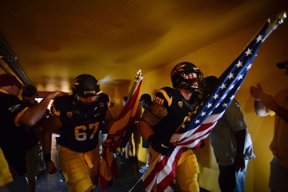 Junior defensive tackle Jake Sheffield walks down the Patt Tillman Memorial Tunnel holding the American flag prior to Saturday's game against UCLA. (Photo by Aaron Lavinsky)