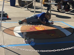 Lisa Bernal Brethour puts her finishing touches on her most recent street art mural, photographed on Sept. 24. Brethour uses grid lines on the sidewalk to help create the intricate details.