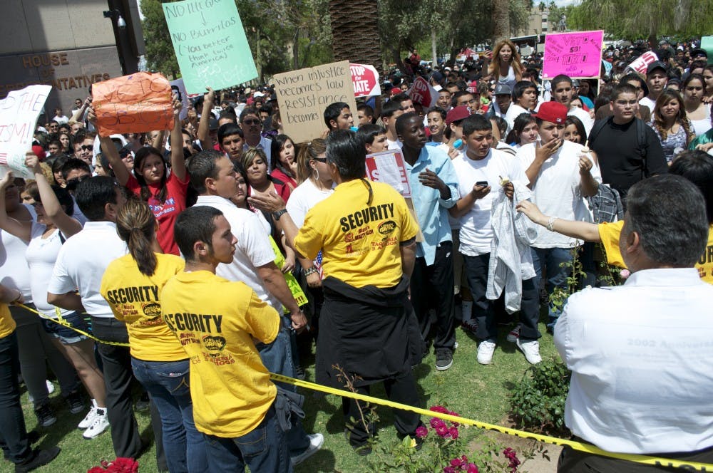 Volunteer security people work to keep protesters behind the caution tape on the Capitol lawn Friday afternoon. (MOLLY SMITH | THE STATE PRESS)