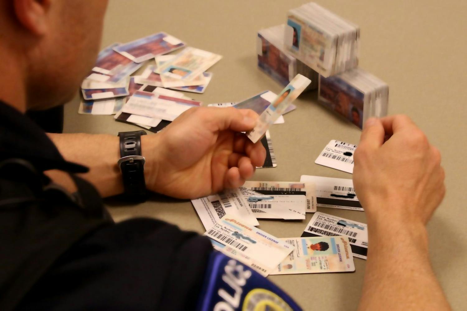 Officer Anthony Kinsey reviews the seized ID's held at the ASU Police Department in Tempe on Tuesday, Jan. 12, 2016.