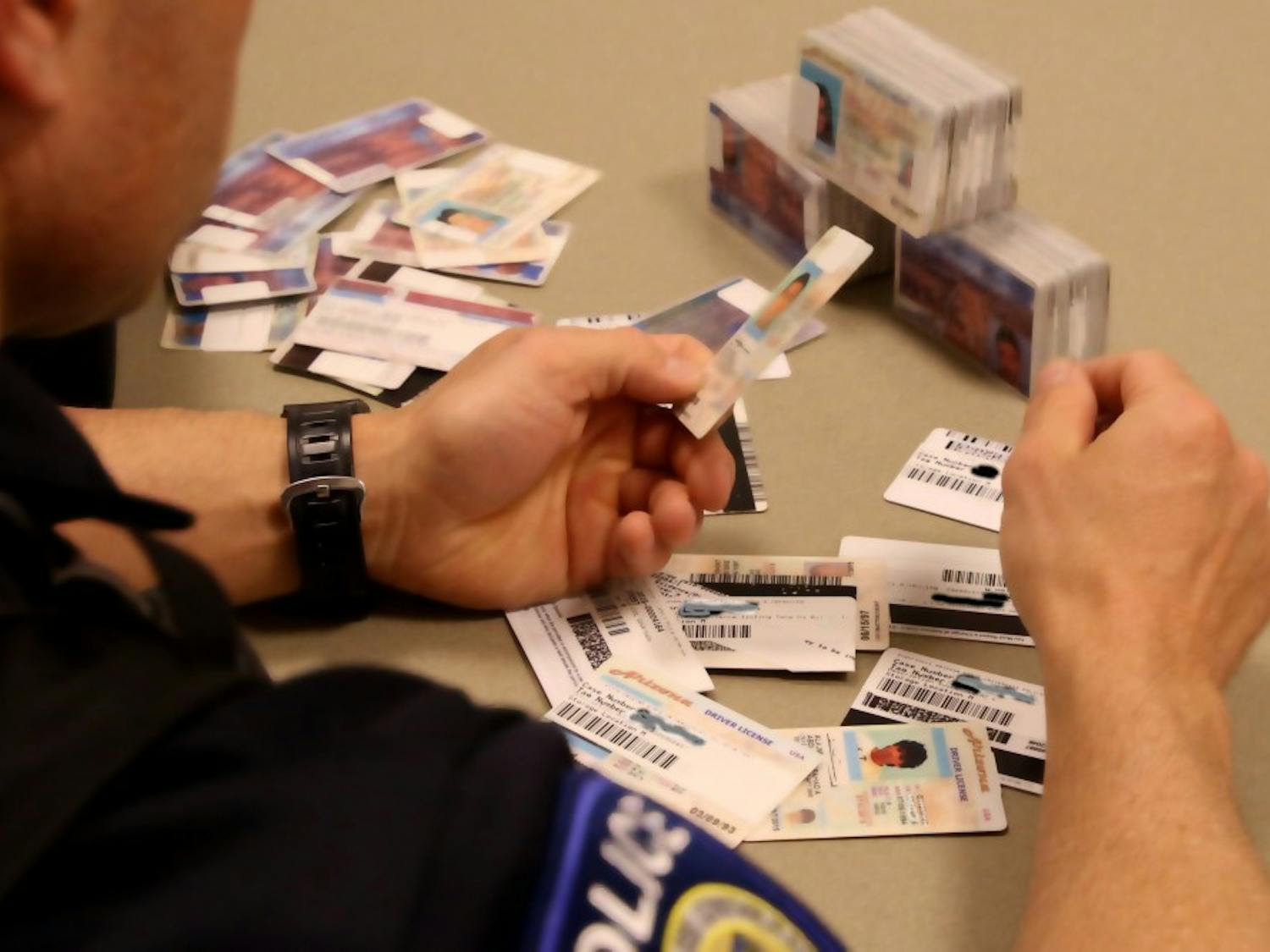 Officer Anthony Kinsey reviews the seized ID's held at the ASU Police Department in Tempe on Tuesday, Jan. 12, 2016.