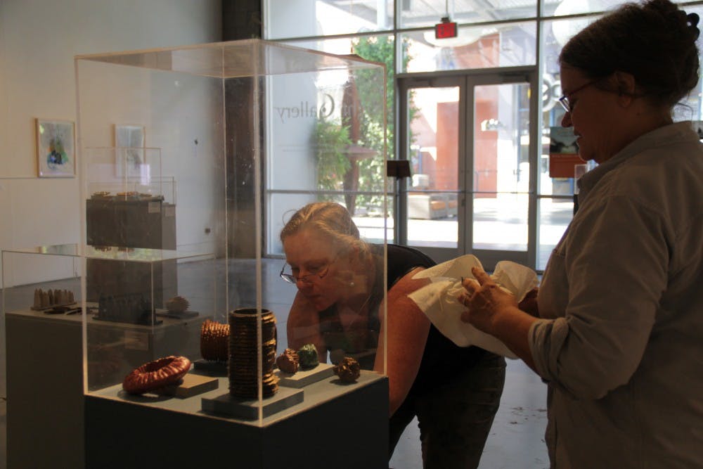 Mary Hood, associate professor in the school of art and Mary Neubauer, professor in the school of art, prepare the Night Gallery at Tempe Marketplace on Thursday afternoon for the Third Wave Art Exhibit, which opens Friday. (Photo by Shawn Raymundo)