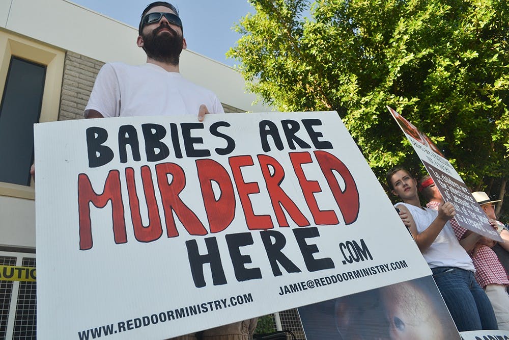 Zach Ary Conover holds a sign at a rally against Planned Parenthood in downtown Phoenix on Saturday, Aug. 22, 2015.