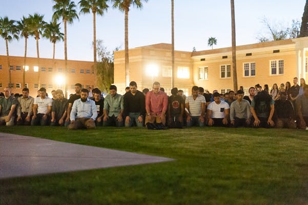 Supporters pray after a candlelight vigil at Hayden Lawn on Thursday. The vigil memorialized the Muslim victims of a shooting in Chapel Hill, North Carolina, earlier this week. (Ben Moffat/The State Press)
