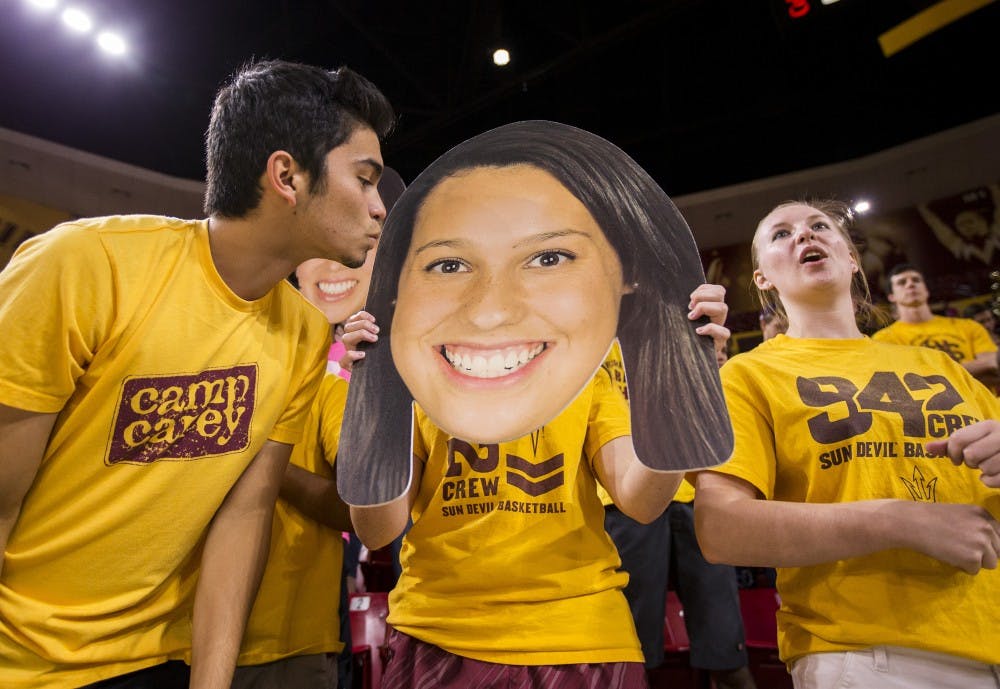 Joey Palomarez, left, leans in to kiss a "fathead" sign of ASU  player Whitney Follette held by Talaya Thomas, center, in the Inferno at Wells Fargo Arena in Tempe on Friday, Oct. 2, 2015.