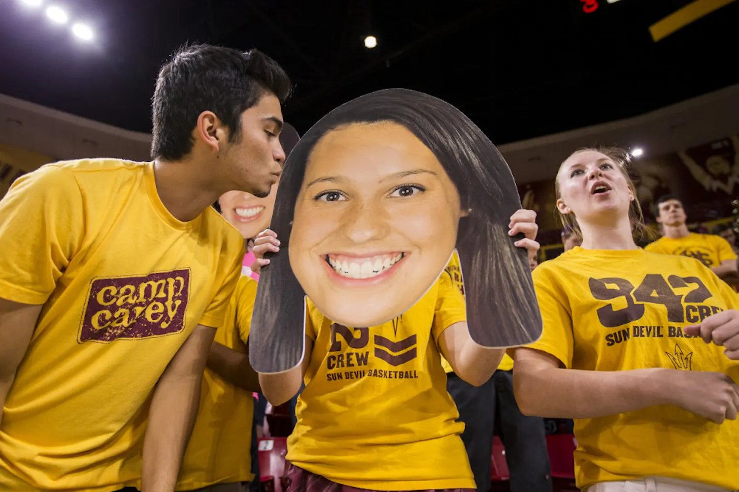 Joey Palomarez, left, leans in to kiss a "fathead" sign of ASU player Whitney Follette held by Talaya Thomas, center, in the Inferno at Wells Fargo Arena in Tempe on Friday, Oct. 2, 2015.
