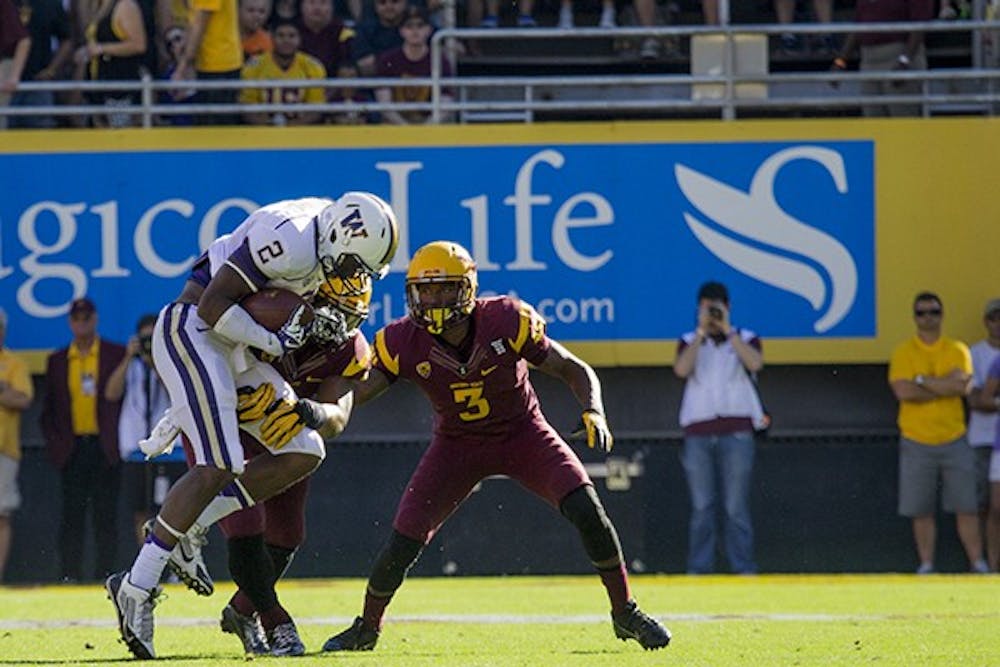 Senior outside linebacker (left) Chris Young makes a tackle while redshirt junior defensive back (right) Damarious Randall assists. ASU defeated the Washington Huskies this weekend and have thus far remained undefeated at home. (Photo by Dominic Valente) 