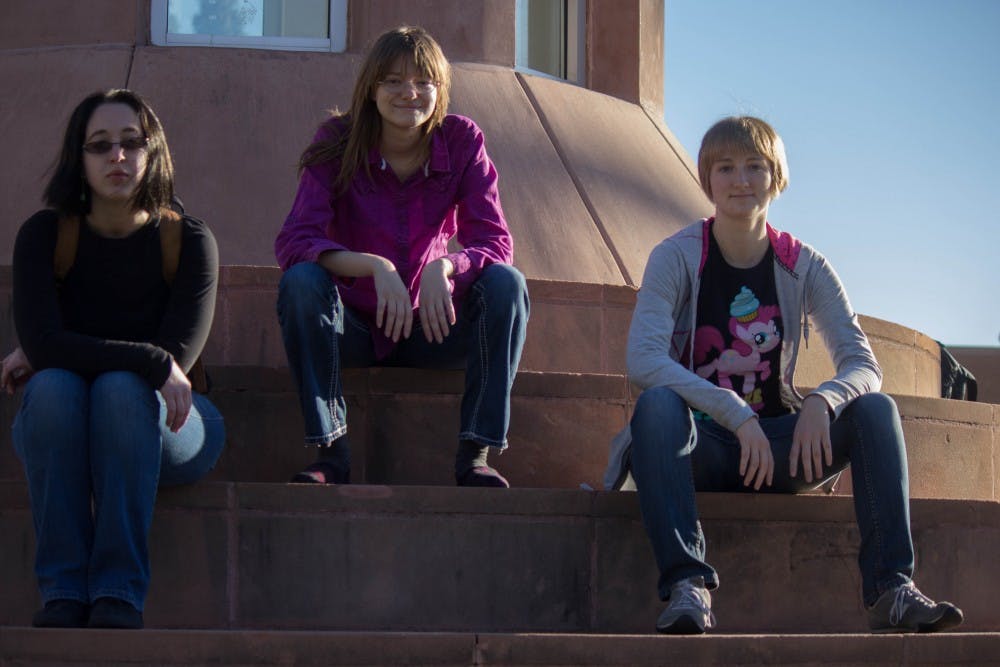 Nicole Lemme, Abigail Daniels and Danielle Farley sit in Hayden Lawn. They consist of an activist group that puts up feminist signs around campus. (Photo by Dominic Valente)
