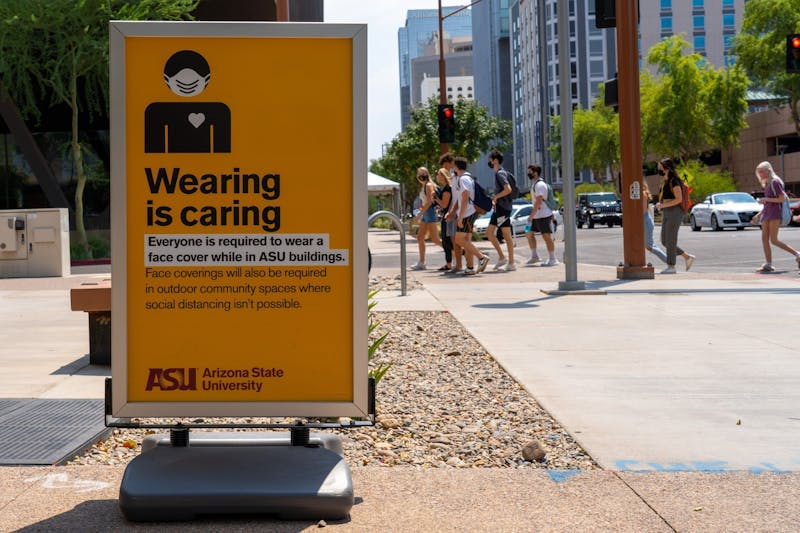 Unos de las señales de ASU que dice "Llevar es Cuidar" se ilustra mientras los estudiantes caminan hacia los dormitorios de Taylor Place el jueves, 20 de agosto de 2020, en el Campus del Centro de Phoenix de ASU.