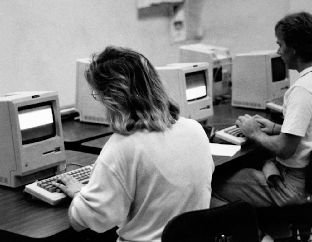 TECHNOLOGY CHANGES FAST: Caryl Grossman, left, and Don Empie, right, use Macintosh computers in their reporting labs in the Journalism department in the ‘80s. (Photo by State Press Photo Staff)