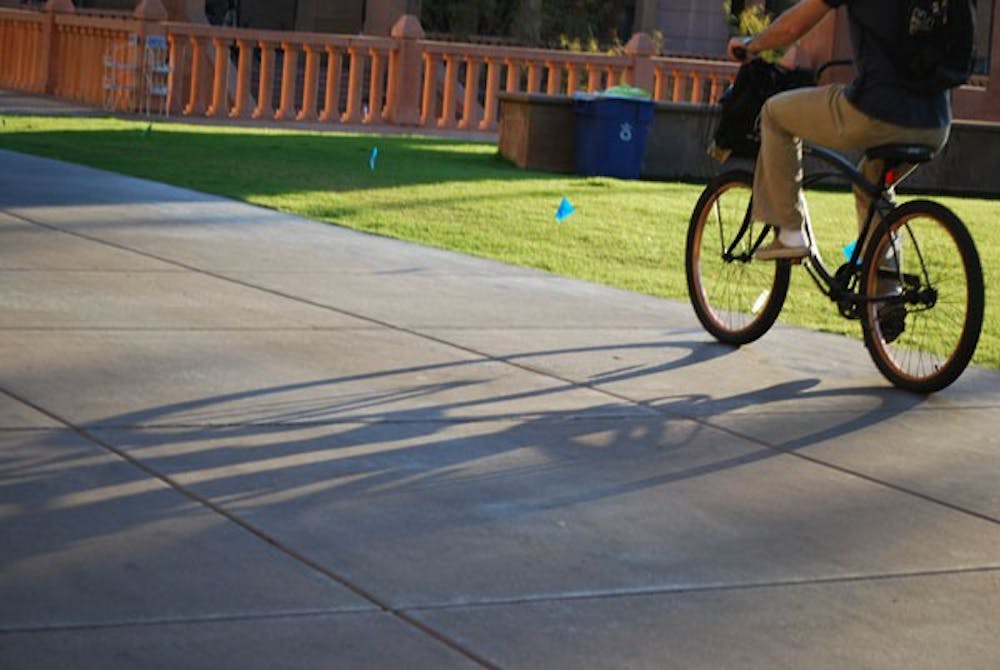 A student bikes down Cady Mall and past Hayden Lawn on the Tempe campus. (Photo by Murphy Bannerman)